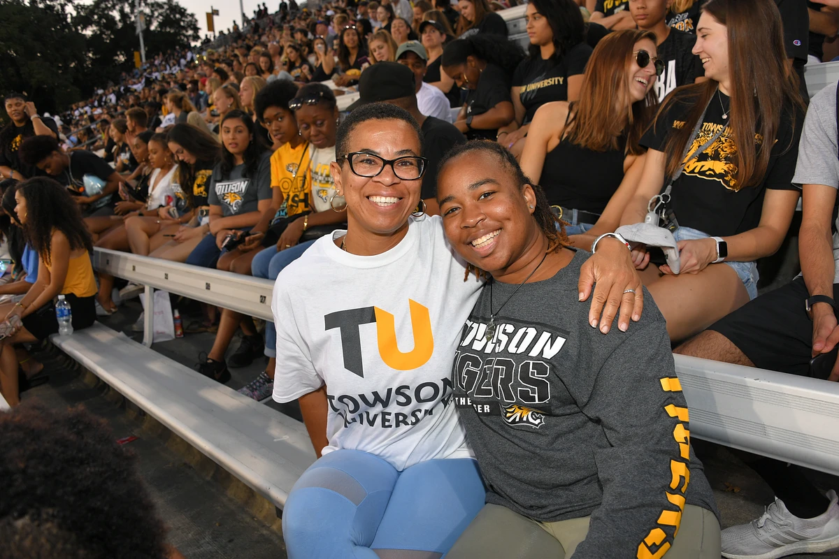 Two people smiling in the stands at the football game